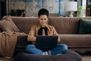 a woman sits on her couch, comparing prescription prices on her computer