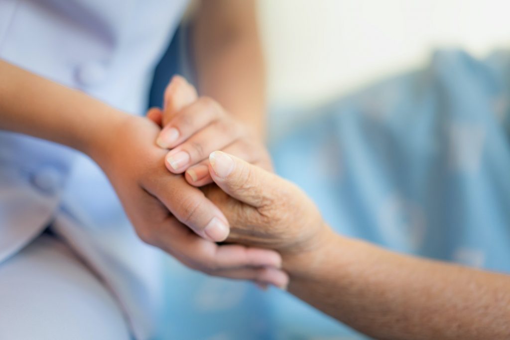 A Patient Assistance Program medical professional holds a patient's hand.