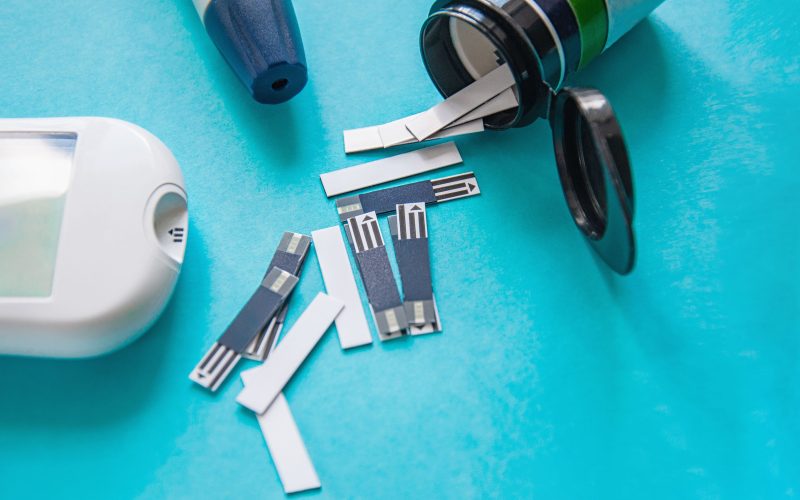 Diabetes. Glucometer. A device for measuring blood sugar levels. Test strips on a blue background. Prevention of diabetes, the concept of health and a healthy lifestyle. Copy space
