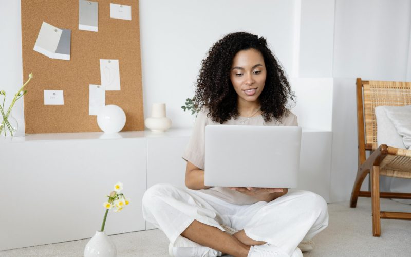 a woman smiles as she sits at her computer in her room